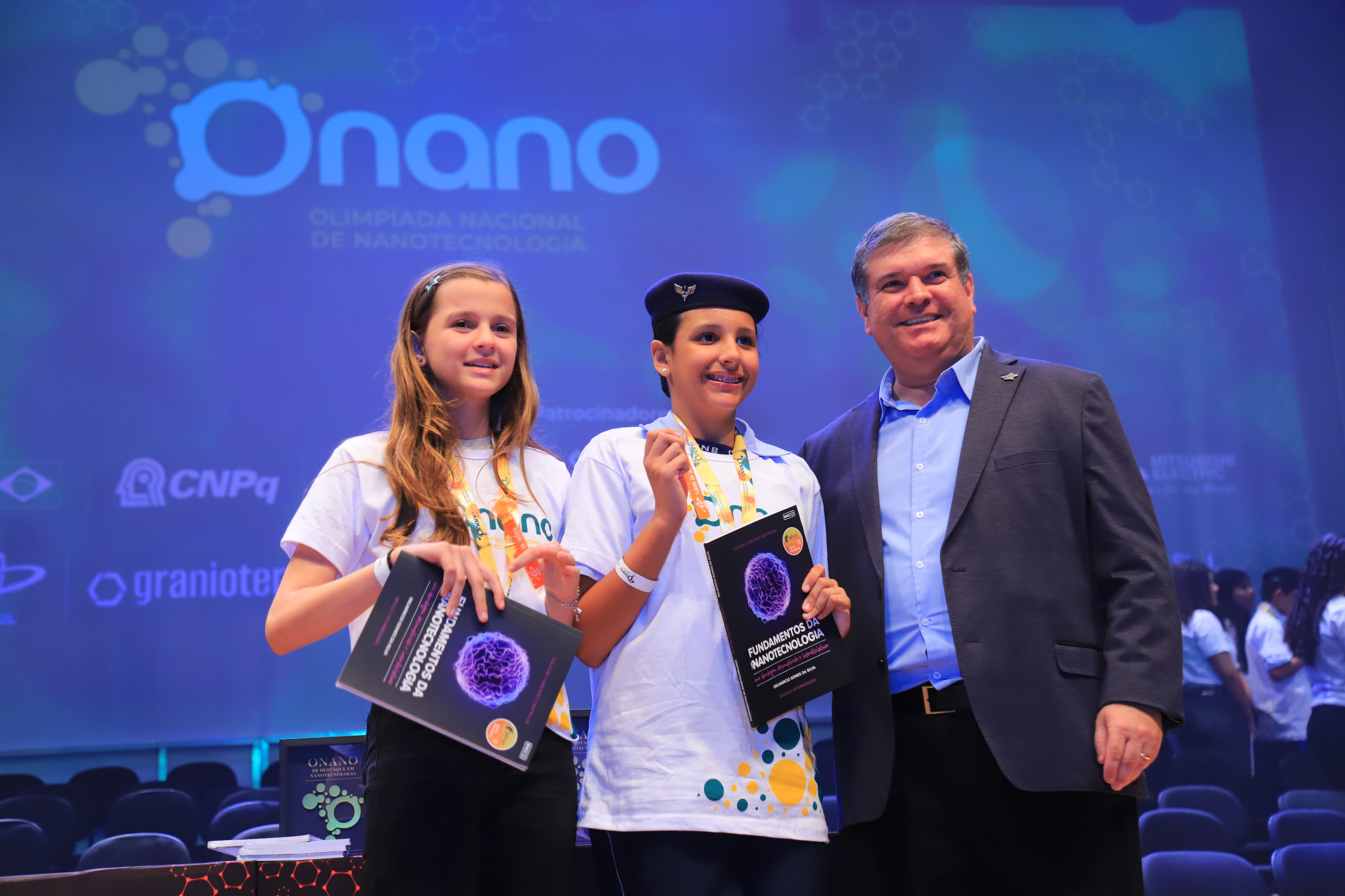 Estudantes recebendo o livro Fundamentos da Nanotecnologia na premiação da ONANO